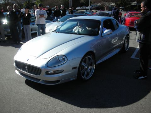 1998 Ford Crown Victoria - silver Maserati coupe front three-quarter at an outdoor car show, with the trident grille and chrome wheels visible.