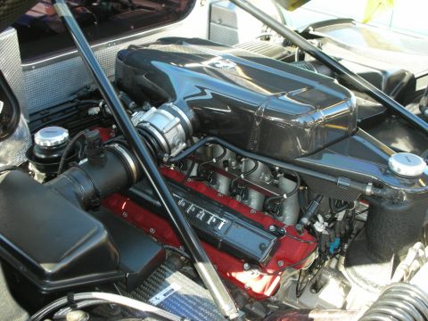 1998 Ford Crown Victoria - Detailed view of a Ferrari V12 engine, its red cam covers reading Ferrari beneath a carbon-fiber intake plenum.