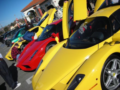 1998 Ford Crown Victoria - line of yellow and red Ferrari Enzos with scissor doors raised at a sunny outdoor car gathering with spectators.