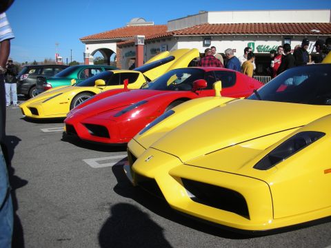 1998 Ford Crown Victoria - row of yellow and red Ferrari Enzos parked in front of a Spanish-tile strip mall at a crowded car meet.