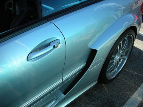 1998 Ford Crown Victoria - Close-up of a silver Mercedes coupe's flank, highlighting the door handle, side fender vent, and a multi-spoke chrome wheel.