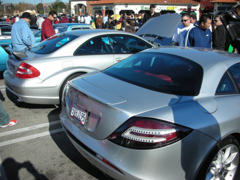 1998 Ford Crown Victoria - silver Mercedes-Benz SLR McLaren and a CLK parked side by side at a busy outdoor car meet, California plate visible.
