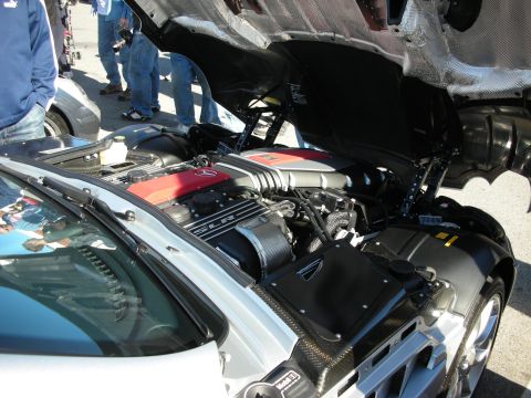 1998 Ford Crown Victoria - clamshell hood of a silver Mercedes SLR McLaren raised to show its red-topped supercharged V8 and carbon-fiber trim.