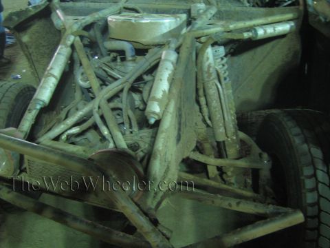 Close-up of the muddy tube-frame chassis and engine bay of an off-road buggy