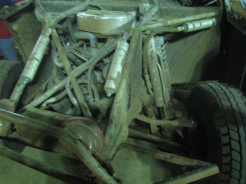Close-up of the mud-covered front tube chassis and engine of an off-road buggy