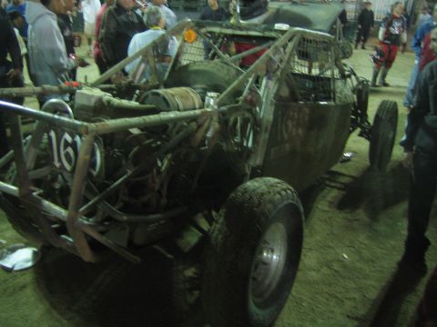 Tube-frame off-road buggy number 161 with rear engine on arena dirt at night