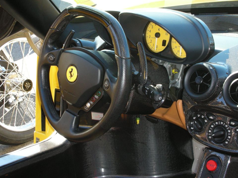 Ferrari cockpit with carbon dash, yellow gauges and a wire wheel visible outside