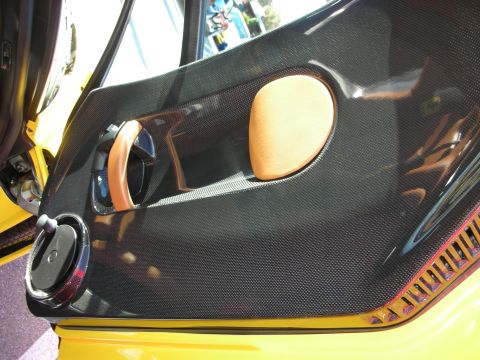 1998 Ford Crown Victoria - carbon-fiber inner door panel of a yellow sports car, fitted with a tan leather armrest and door-pull strap.