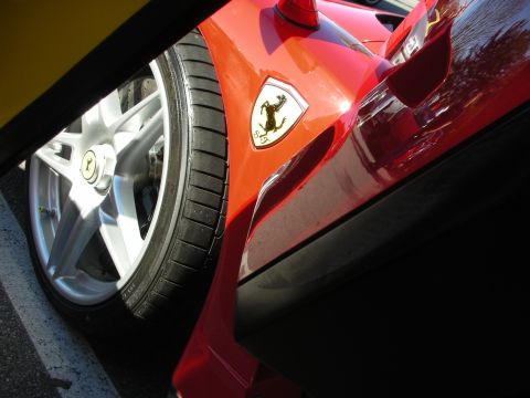 1998 Ford Crown Victoria - low-angle shot of a red Ferrari's silver alloy wheel and front fender, marked with the yellow prancing-horse shield.