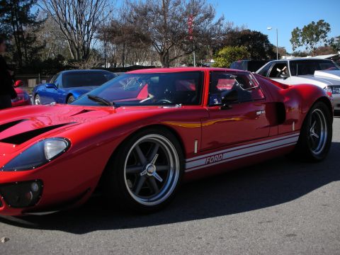 1998 Ford Crown Victoria - red GT40-style sports car with white side stripes and Ford lettering, low and wide on five-spoke wheels at a show.