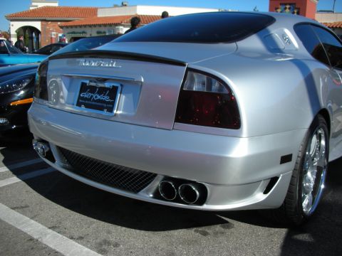 1998 Ford Crown Victoria - Rear three-quarter view of a silver Maserati coupe with quad tailpipes, lip spoiler and a dealer license-plate frame.