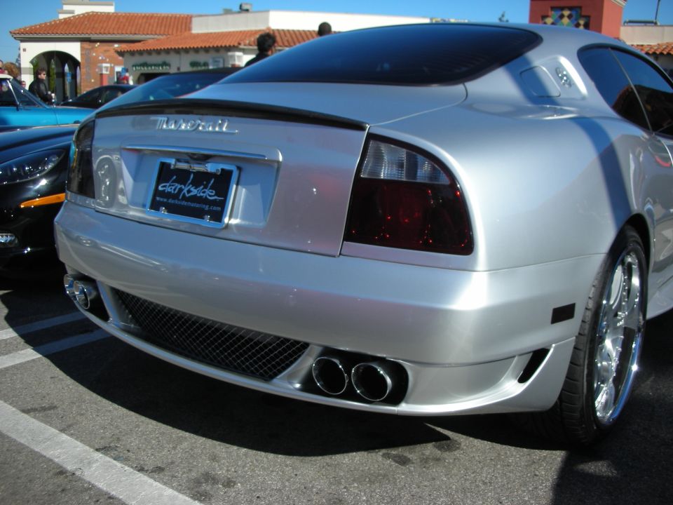 Rear of a silver Maserati coupe showing quad exhaust and dealer plate frame
