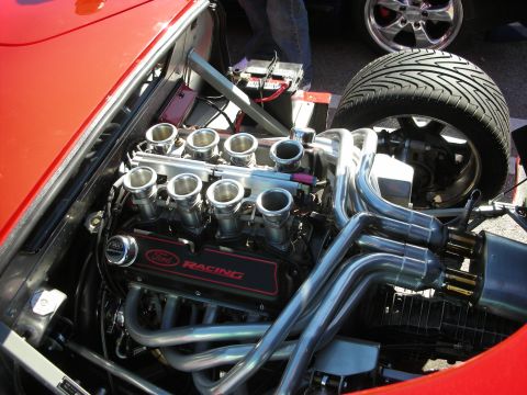 1998 Ford Crown Victoria - Detailed view of a Ford Racing V8 with eight individual throttle bodies and bundled chrome headers in a red kit car's engine bay.