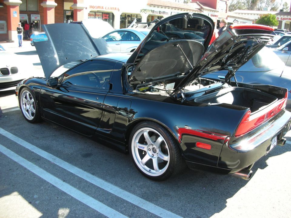 Black Acura NSX with hood and rear hatch open at a shopping-center car show