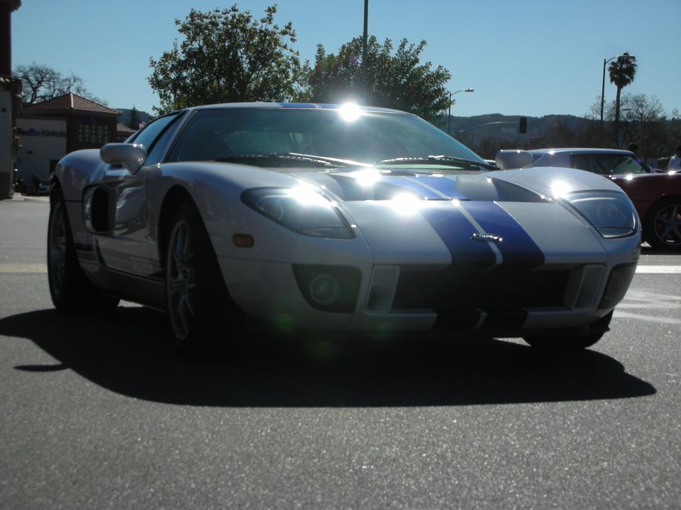 Silver Ford GT with blue racing stripes and headlights on, front view