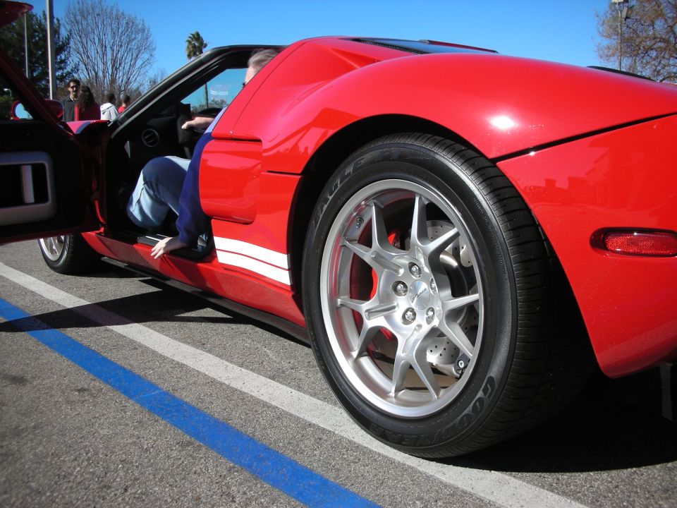 Low rear-quarter view of a red sports car with silver multi-spoke wheel
