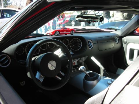 1998 Ford Crown Victoria - Interior of a sports car with a black three-spoke steering wheel, round gauges, center vents and an exposed gated shifter.