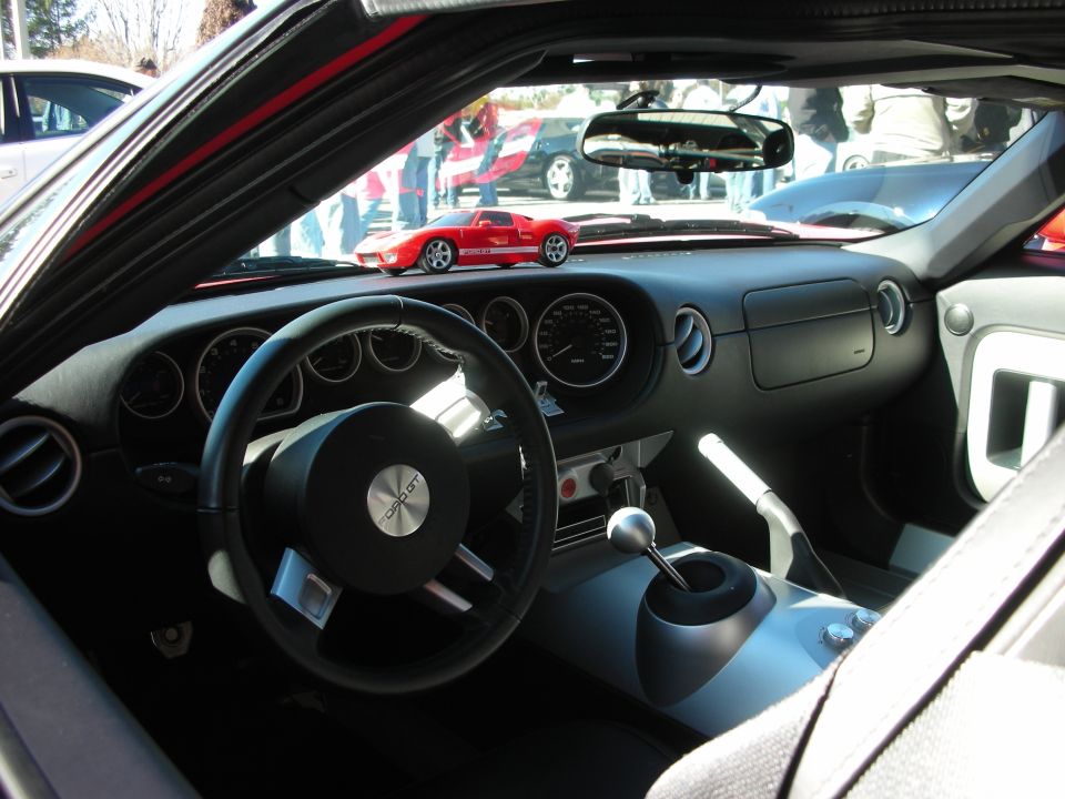 Black sports car interior with three-spoke wheel, gauges and exposed shifter