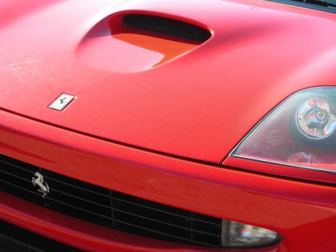 1998 Ford Crown Victoria - Front hood detail of a red Ferrari showing the prancing-horse badge, a hood vent and one headlight.