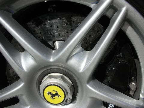 1998 Ford Crown Victoria - Close-up of a silver Ferrari alloy wheel with the yellow prancing-horse center cap, drilled rotor and dark brake caliper behind it.
