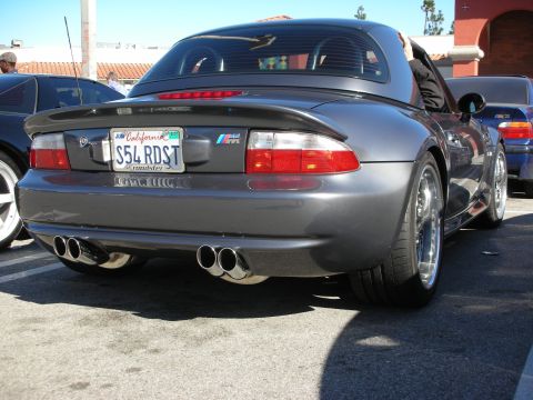 1998 Ford Crown Victoria - Gray BMW M roadster shot from the rear showing M badge, quad exhaust outlets and a California 'S54 RDST' license plate.