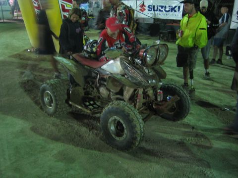 Sport ATV with rider at night under a Suzuki banner