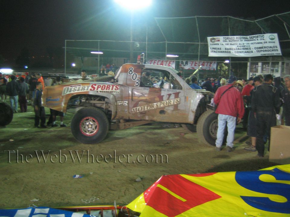 Tan off-road race truck number 803 with Desert Sports decals at night