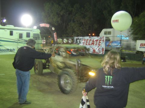 Off-road buggy at night with man pointing and woman in Monster hoodie