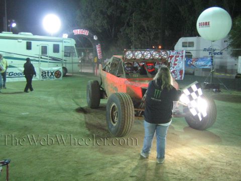 Red off-road buggy with light bar at night, flagger in Monster hoodie