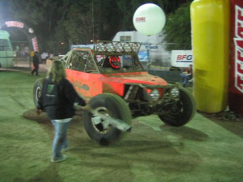 Orange off-road buggy turning at night near inflatable arch, flagger present