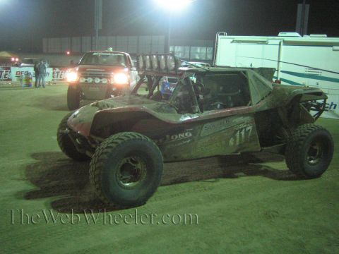 Off-road buggy number 117 with chase pickup behind it in a night paddock