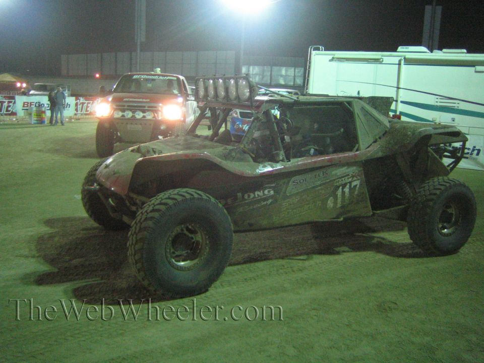 Off-road buggy number 117 with chase pickup behind it in a night paddock