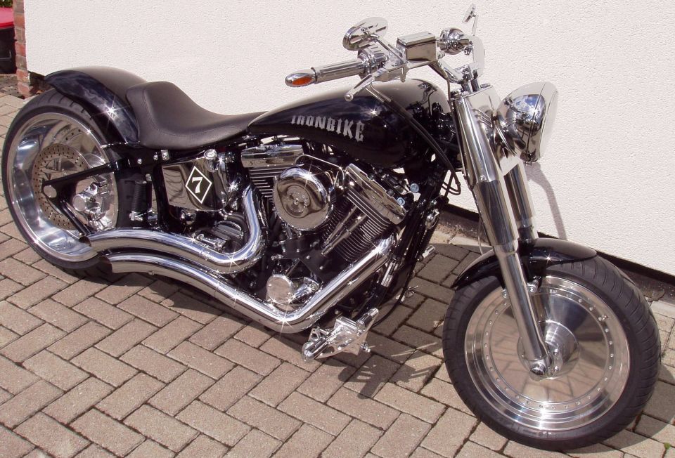 Black custom cruiser motorcycle with chrome engine and 'IRONBIKE' tank on brick pavers