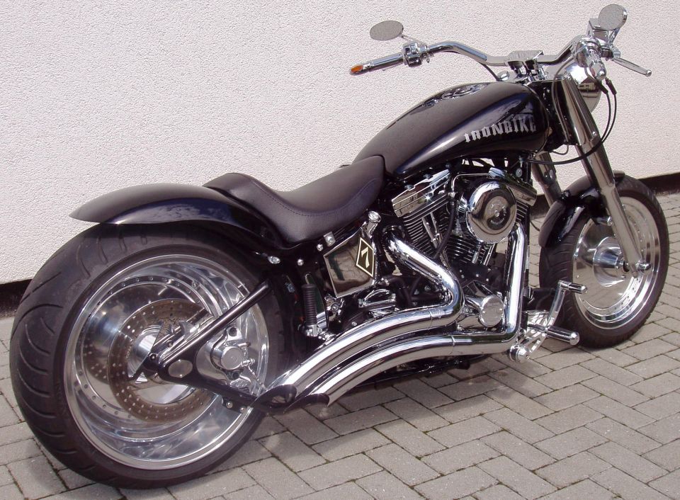 Black custom Harley cruiser with chrome exhaust and solid rear wheel, 'IRONBIKE' on tank