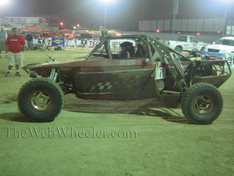 Single-seat off-road race buggy on dirt at a nighttime event