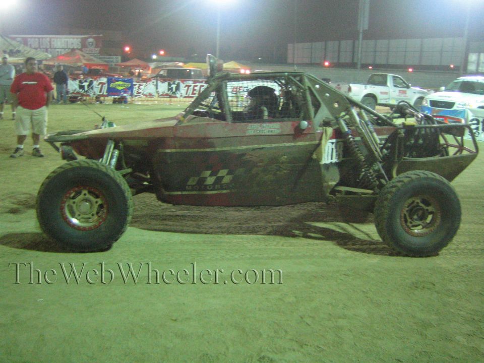 Single-seat off-road race buggy on dirt at a nighttime event