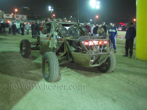 Front view of a tube-frame off-road buggy before a crowd at night