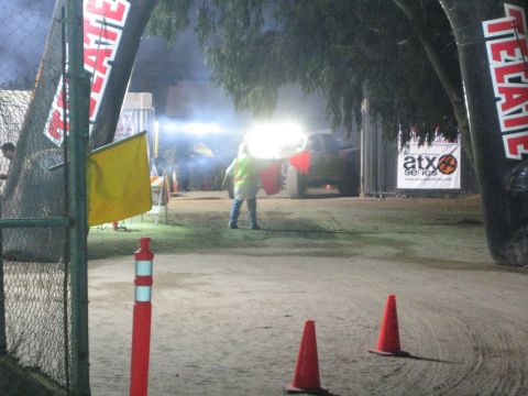 Course marshal in vest by a lit Tecate inflatable arch at night