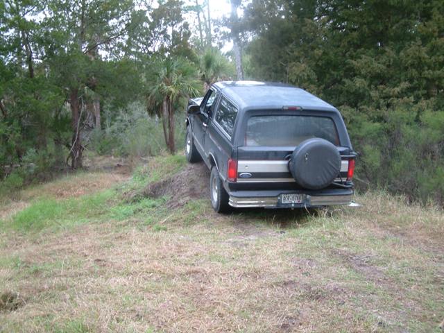 Black 1992 Ford Bronco parked on a grassy incline, rear view