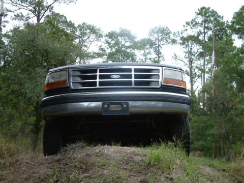 1992 Ford Bronco - Front view of a 1992 Ford Bronco on a dirt path with trees in the background.