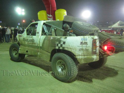 Muddy off-road race truck with spare tire and yellow fuel jugs