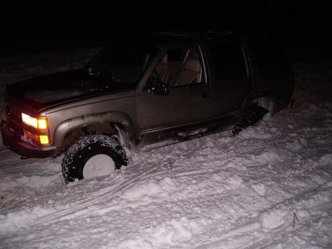 2000 Chevrolet Tahoe - This gold SUV appears to be stuck in a snowdrift, with its front wheel deep in the snow.