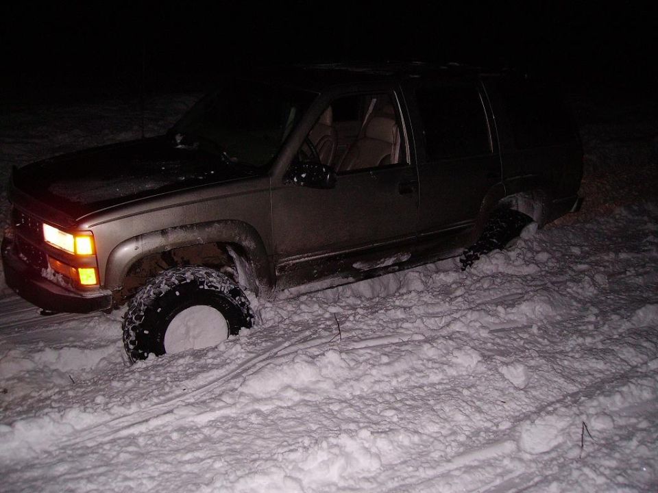 Gold SUV stuck in deep snow, front wheel submerged