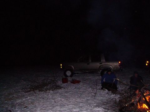 2000 Chevrolet Tahoe - An SUV is parked in a snowy area at night while people gather around a campfire.