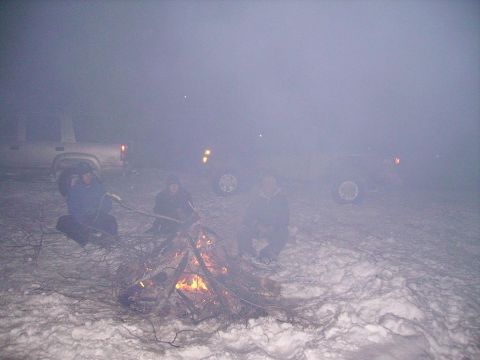 2000 Chevrolet Tahoe - Campfire scene in the snow with vehicles present.