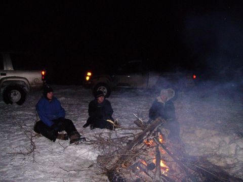 2000 Chevrolet Tahoe - People gather around a bonfire in a snowy, dark environment, with vehicles visible in the distance.