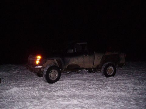 2000 Chevrolet Tahoe - A dark Chevrolet Silverado pickup truck is seen from the front passenger side, parked in a snowy area at night.