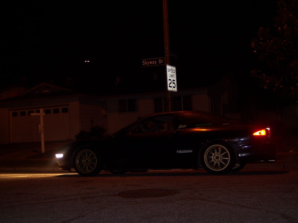 Dark coupe with aftermarket wheels parked at night on a residential street