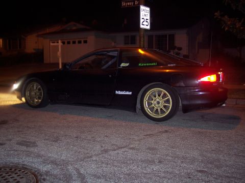 1995 Ford Probe - This black coupe with gold rims is seen parked on a residential street at night.