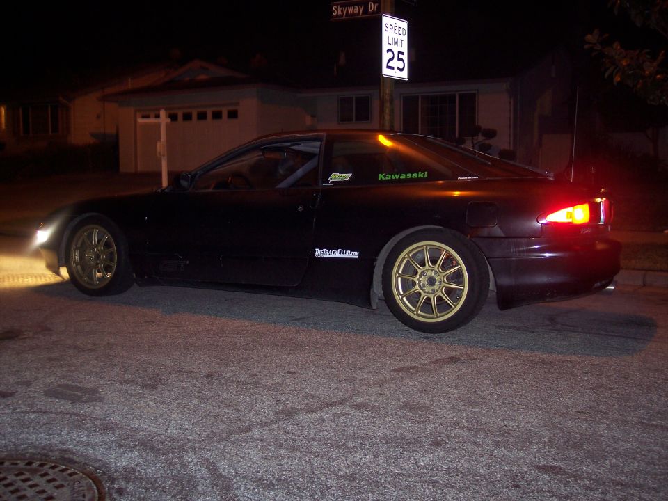 Black coupe with gold rims parked at night